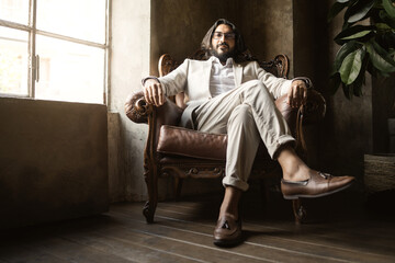portrait of middle-eastern businessman wearing eyeglasses in a proud posture sitting comfortably on an armchair