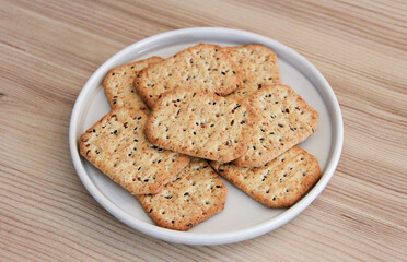 Dry square diet crackers with black cumin seeds and quinoa in a decorative plate