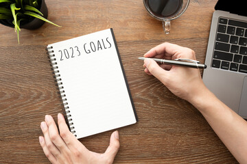 Man is writing 2023 goals for new year resolutions plan.