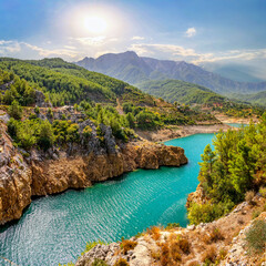 Beautiful landscape of mountainous nature with bright summer sun, blue sky, high mountains, green hills, yellow rocks and turquoise water lake.