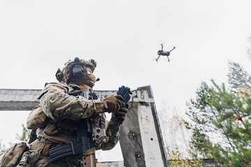 Military soldier controls drone for reconnaissance operation of enemy positions. Concept using quadrocopters in smart war - obrazy, fototapety, plakaty