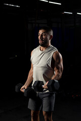 Fototapeta na wymiar latin man doing biceps work in the gym with two dumbbells