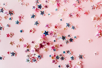 Pink, blue and yellow holographic Stars Glitter Confetti on pink background. Festive backdrop