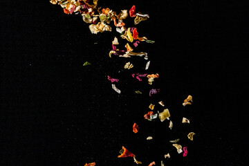 Multi-colored bright spices and peppers in flight on a black background