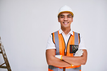 Portrait of an Asian construction worker smiling with arms crossed, white wall
