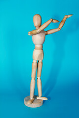 yellow wooden mannequin poses and gestures with his hands on a blue background