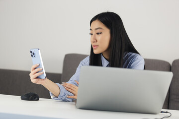Young asian female talking on frontal camera of smartphone. Vietnamese girl speaking on video call