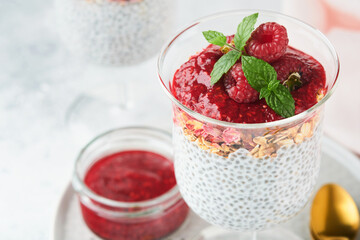 Chia pudding. Healthy vanilla chia pudding in glass with fresh raspberries and mint on white background. Vegan healthy breakfast.