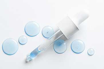 Drops of cosmetic serum and a pipette. A skin care product. White background. Copy space.