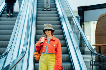 Redhead hipster young woman in bright clothes, sun glasses and bucket hat with backpack bag...