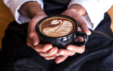 Close up coffee barista hands holding cup of coffee latte art in cafe, Coffee Art Concept