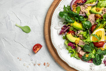 salad with tuna, avocado, lettuce, cherry tomatoes on a light background. Restaurant menu, dieting, cookbook recipe top view