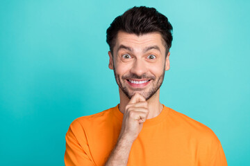 Closeup photo of young handsome pretty nice guy wear orange t-shirt touch bearded chin toothy smile excited positive empty space offer isolated on cyan color background