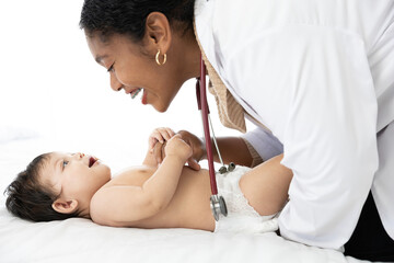 African doctor pediatrician examining and holding baby’s hands on the bed