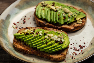 avocado toasts for breakfast or lunch with rye bread, sliced avocado, pumpkin seeds. Food recipe background. Close up