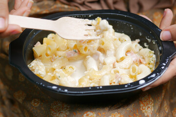 women eating take away cooked pasta in a plastic container 
