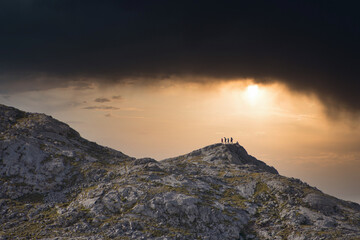 Cima de una montaña con gente celebrando felices al atardecer