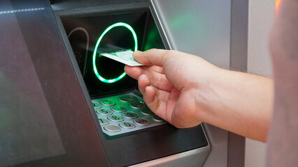 a man inserts the debit card into an ATM