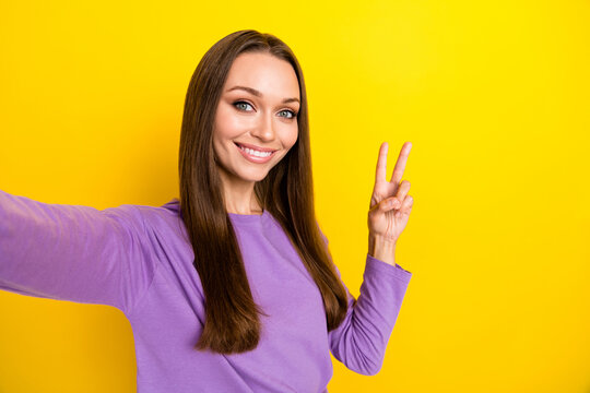 Closeup selfie photo of young charming pretty woman showing v-sign toothy smiling hello symbol peaceful person isolated on yellow color background