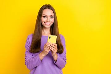 Naklejka premium Photo of young pretty girlish lady wear violet pullover smiling good mood hold her smartphone watching tiktok video isolated on yellow color background