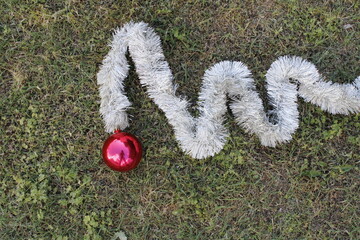 Guirnalda para decoración navideña con pelos blancos y una bola roja en la parte superior sobre el suelo forma un original diseño rústico con un fondo de hierba verde