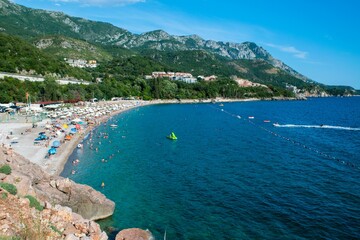 Beautiful landscape of Kamenovo pebble beach located in bay surrounded by green mountains near village of Rafailovici. Budva Riviera. Montenegro.