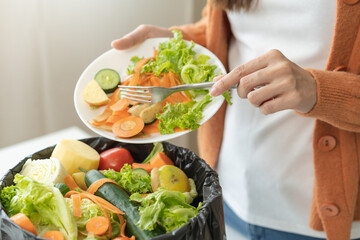Compost from leftover food, asian young housekeeper woman hand holding cutting board use fork scraping waste, rotten vegetable throwing away into garbage, trash or bin. Environmentally responsible. - obrazy, fototapety, plakaty