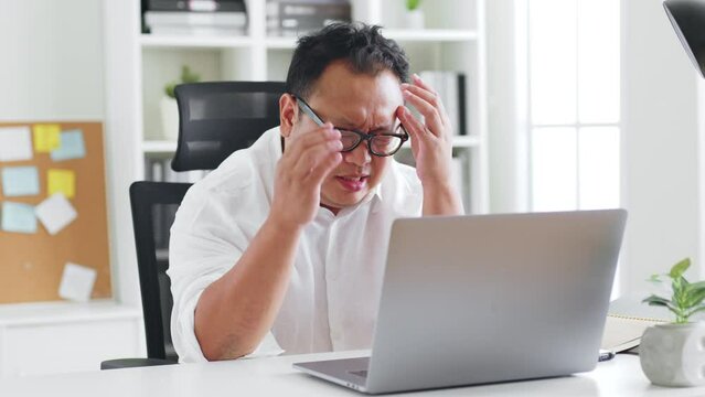 Middle-aged Asian man feel headache, symtom of stroke during working