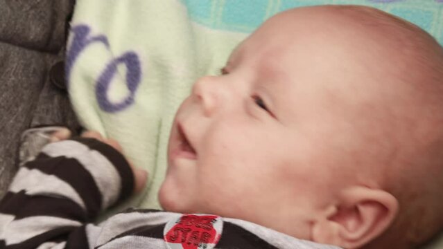 4k footage video. Close up newborn baby child lying in baby carriage stroller buggy having fun playing, looking at her mother, smiling infant. Outside walking in pushchair, fresh air
