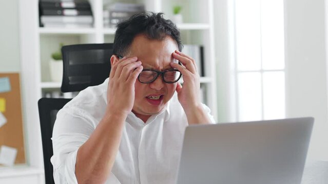 Middle-aged Asian man feel headache, symtom of stroke during working