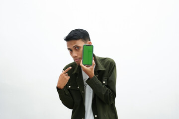 Asian man wearing casual green shirt pointing at smartphone screen. isolated white background.