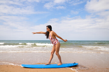 Fototapeta na wymiar Beautiful young latin woman surfing with blue surfboard. The woman is on the beach. Holiday and summer concept.