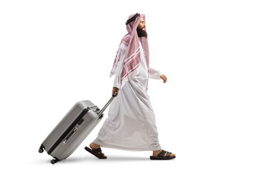 Full length profile shot of a saudi arab man walking and pulling a suitcase