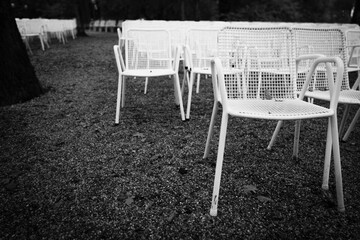 Rows of white metal garden chairs in front of an outdoor stage.