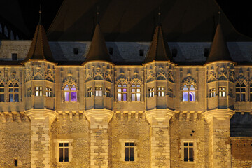Night picture of the facade of the gothic Vajdahunyad (Hunedoara) castle in Romania with colorful windows and towers. Color architectural photo.