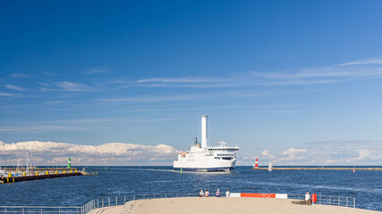 Schiff bzw. Fähre mit Segel, einem Flettner-Rotor, in der Hafeneinfahrt von Rostock Warnemünde
