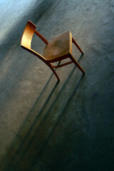 A lonely old, grunge chair in abandoned room with light and shadow falling on the dirty floor....
