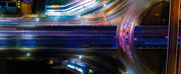 Tuinposter Expressway top view, Road traffic an important infrastructure, car traffic transportation above intersection road in city night, aerial view cityscape of advanced innovation, financial technology  © Hand Robot