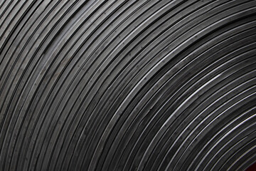 Dynamic abstract dark concentric bands, stripes. Artistic minimal industry photo of a rolled up conveyor belt surface.