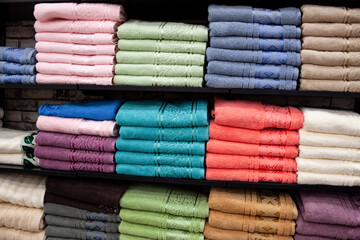 Multicolor towels on shelf in market, sale cotton towels, stack colored cotton towels, a shelf in the home row of the market, close-up selective focus.