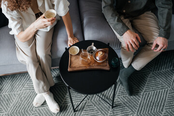 Top view of couple drinking tea sitting on sofa in room.