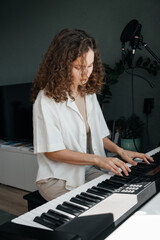 Young woman with curly hair playing music at home.
