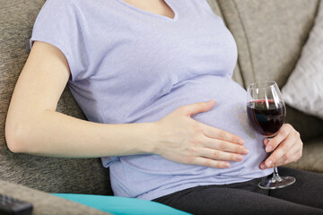 Naklejka premium pregnant woman with glass of wine on white background