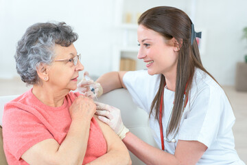 Obraz na płótnie Canvas nurse giving injection to senior woman in the arm