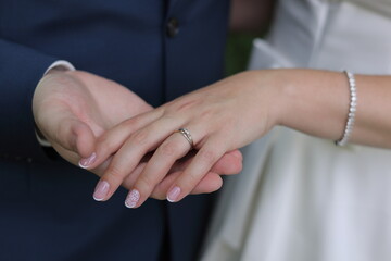 Newlyweds elegant couple are touching and holding each other's hands with engagement ring. Color romantic illustration photo of a happy relationship, wedding or heterosexual lifestyle.