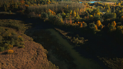 Autumn city park. A meandering river flows between the trees. Trees with colorful leaves. Autumn landscape. Aerial photography.