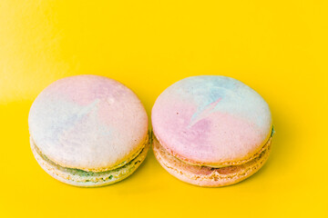 Tasty colorful macaroon. Two blue and pink macaroons on a yellow background. Most delicate cake is a cookie made of two smooth halves, fastened with fillings. French pastry made from egg whites.