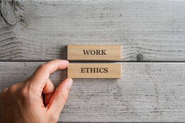 Male hand assembling a Work ethics sign written on two wooden blocks