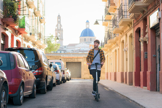 Young man riding an electric scooter through a street