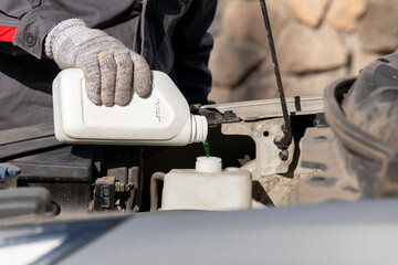 The master at the service center fills the antifreeze into the expansion tank of the car's cooling system. Canister with free space.